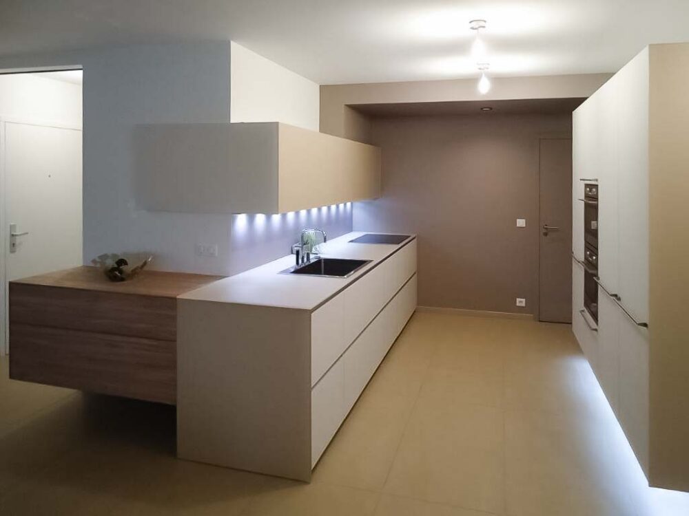 Cuisine en verre beige et blanc avec colonnes suspendues. Éléments en plaquage bois