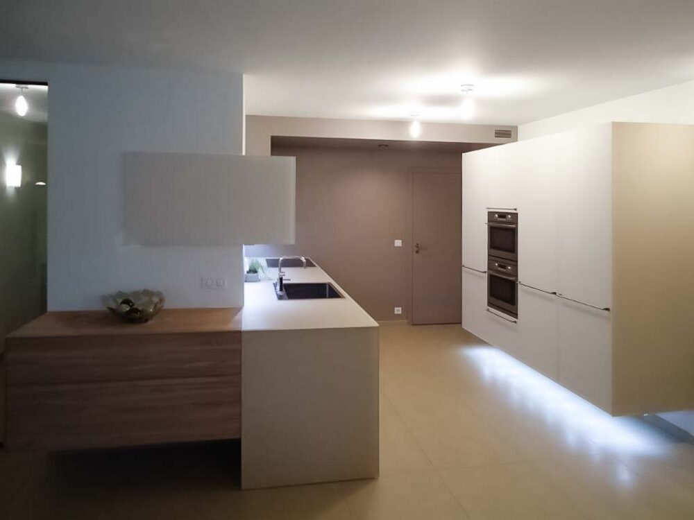 Cuisine en verre beige et blanc avec colonnes suspendues. Éléments en plaquage bois