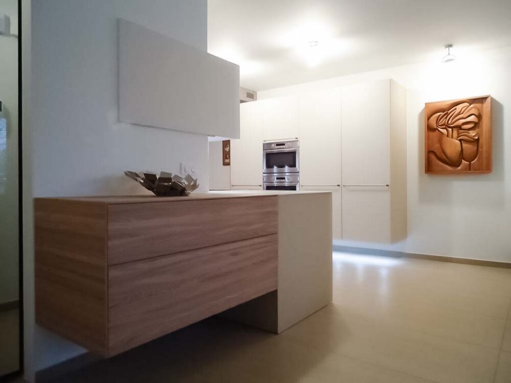 Cuisine en verre beige et blanc avec colonnes suspendues. Éléments en plaquage bois