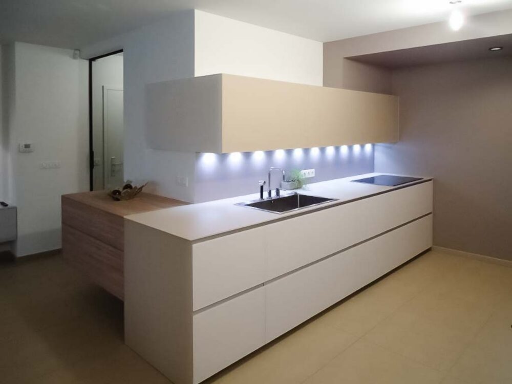 Cuisine en verre beige et blanc avec colonnes suspendues. Éléments en plaquage bois