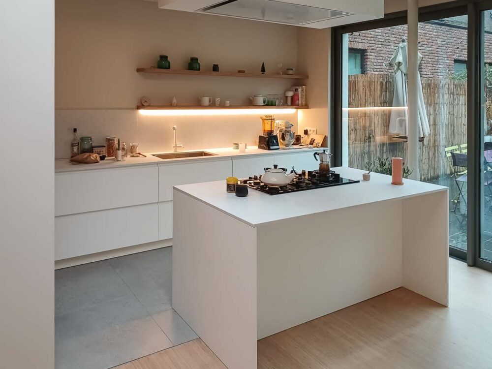 Cuisine avec meuble bas laqué blanc mat, colonnes en plaqué chêne et plan de travail en marbre reconstitué