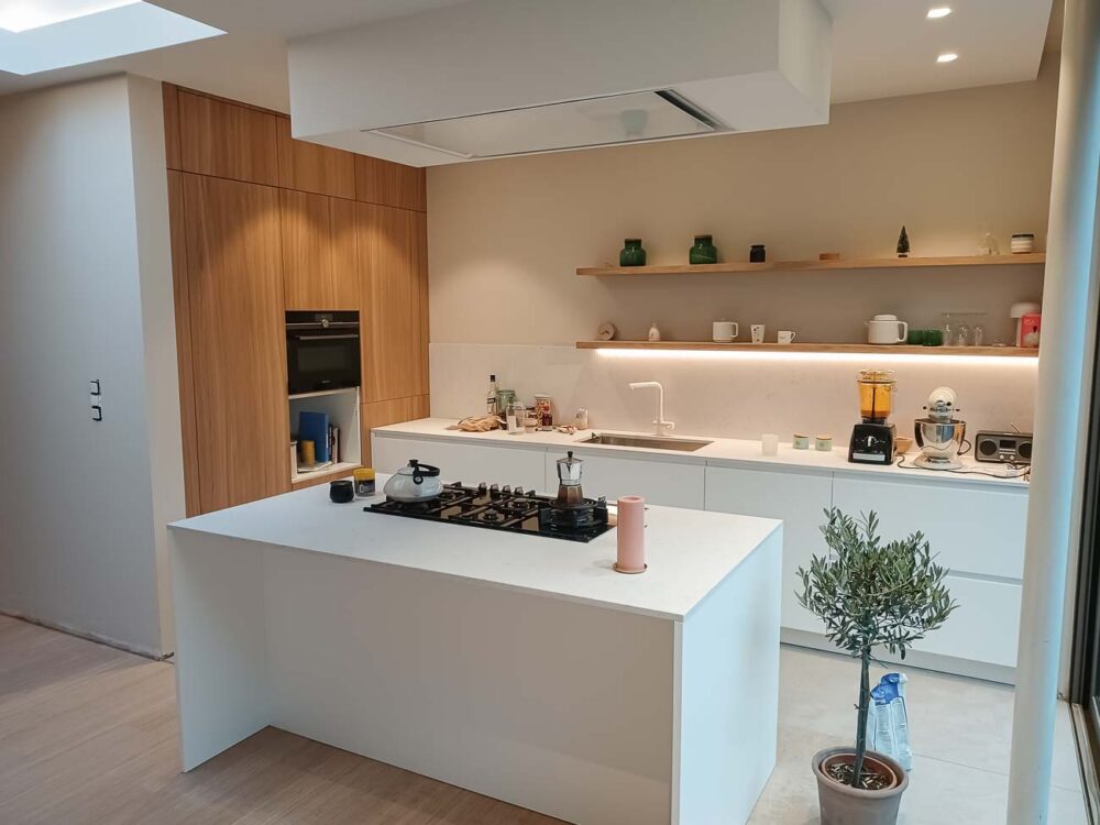 Cuisine avec meuble bas laqué blanc mat, colonnes en plaqué chêne et plan de travail en marbre reconstitué