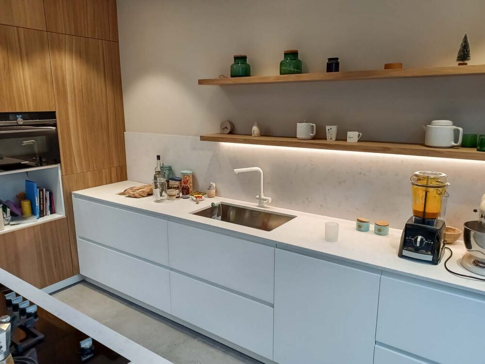 Cuisine avec meuble bas laqué blanc mat, colonnes en plaqué chêne et plan de travail en marbre reconstitué