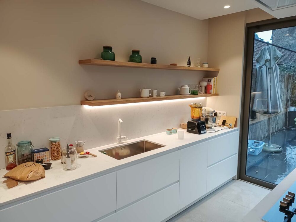 Cuisine avec meuble bas laqué blanc mat, colonnes en plaqué chêne et plan de travail en marbre reconstitué