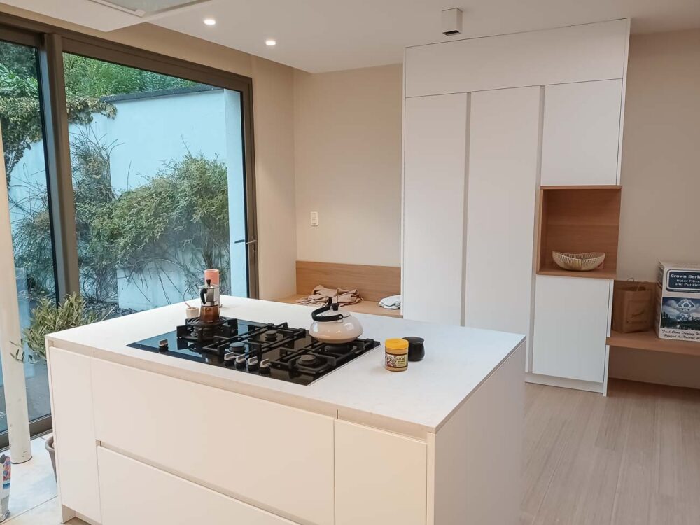 Cuisine avec meuble bas laqué blanc mat, colonnes en plaqué chêne et plan de travail en marbre reconstitué