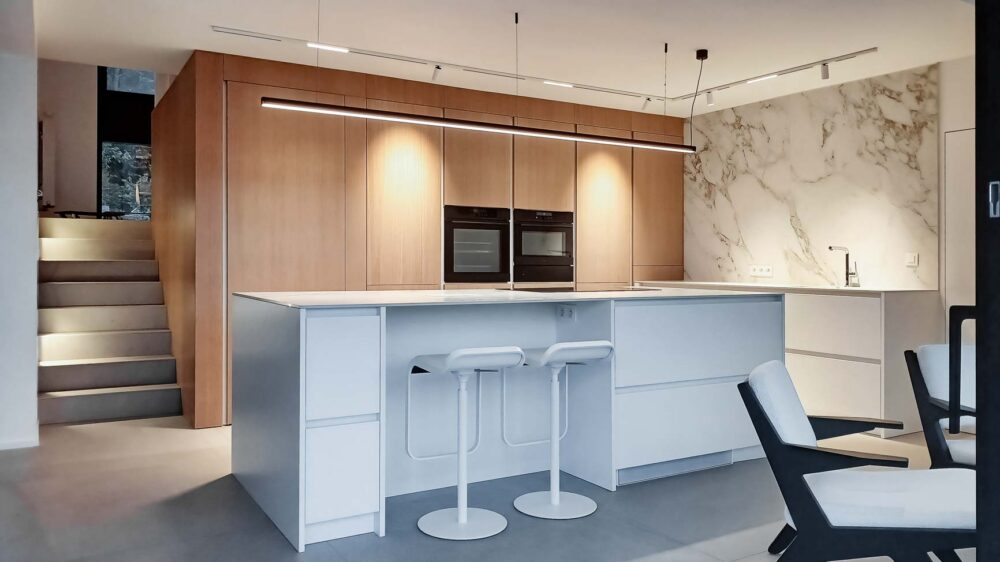 Cuisine blanche minimaliste, meubles bas laqué mat blanc et colonne en plaqué Chêne. Plan de travail et crédence en céramique