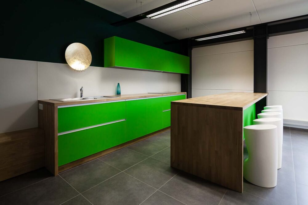 Cuisine d’entreprise en verre vert et bois massif, avec luminaires et salle de réunion