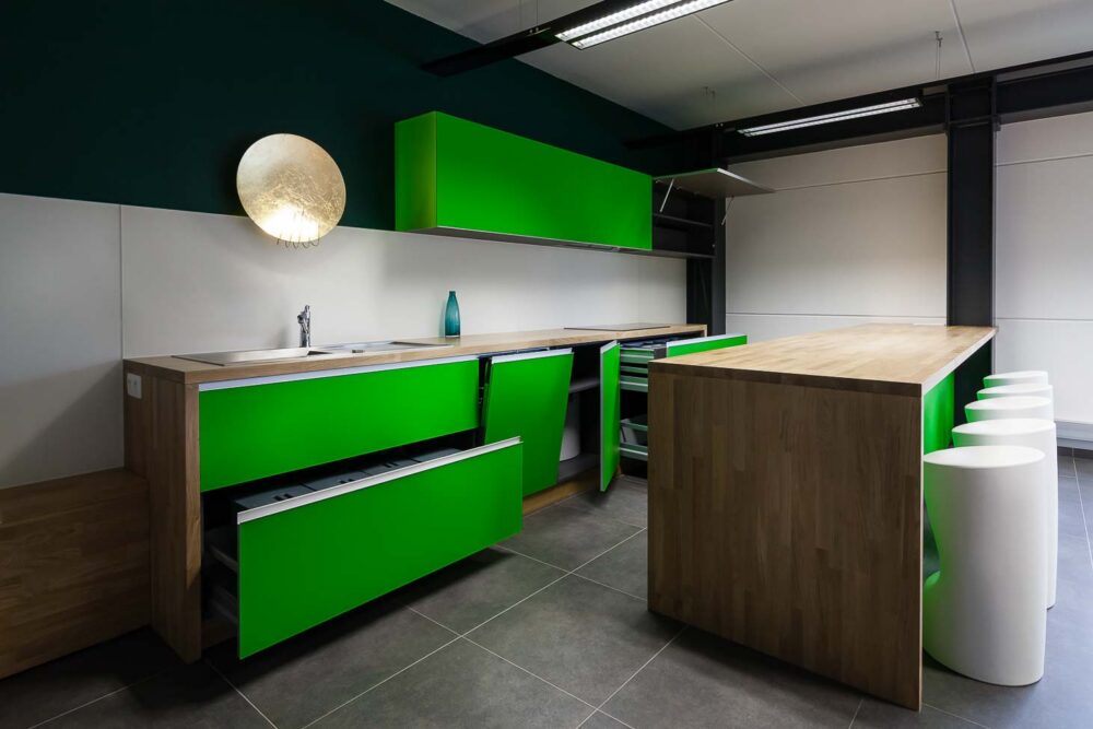 Cuisine d’entreprise en verre vert et bois massif, avec luminaires et salle de réunion