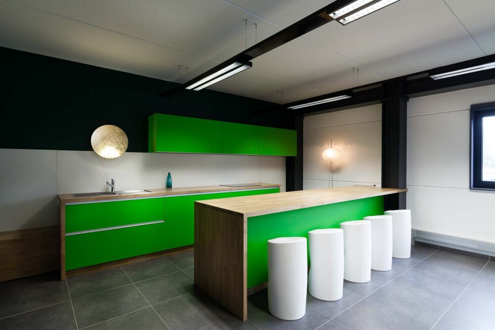 Cuisine d’entreprise en verre vert et bois massif, avec luminaires et salle de réunion