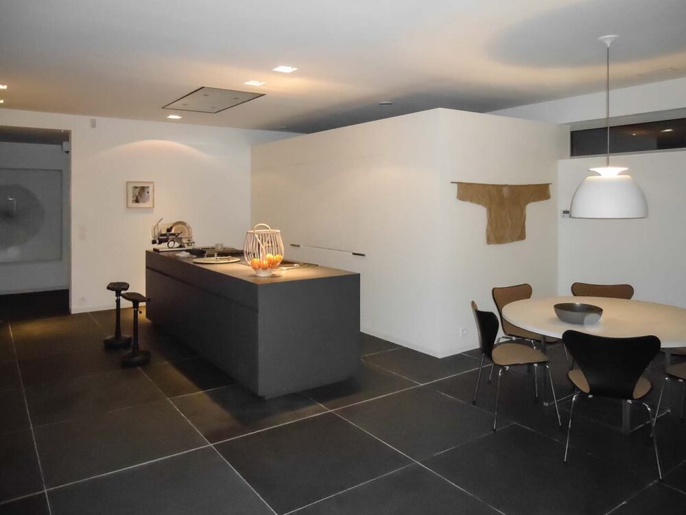 Cuisine sobre avec îlot noir et meuble caché dans un mur avec arrière cuisines et électro invisible sur mesure