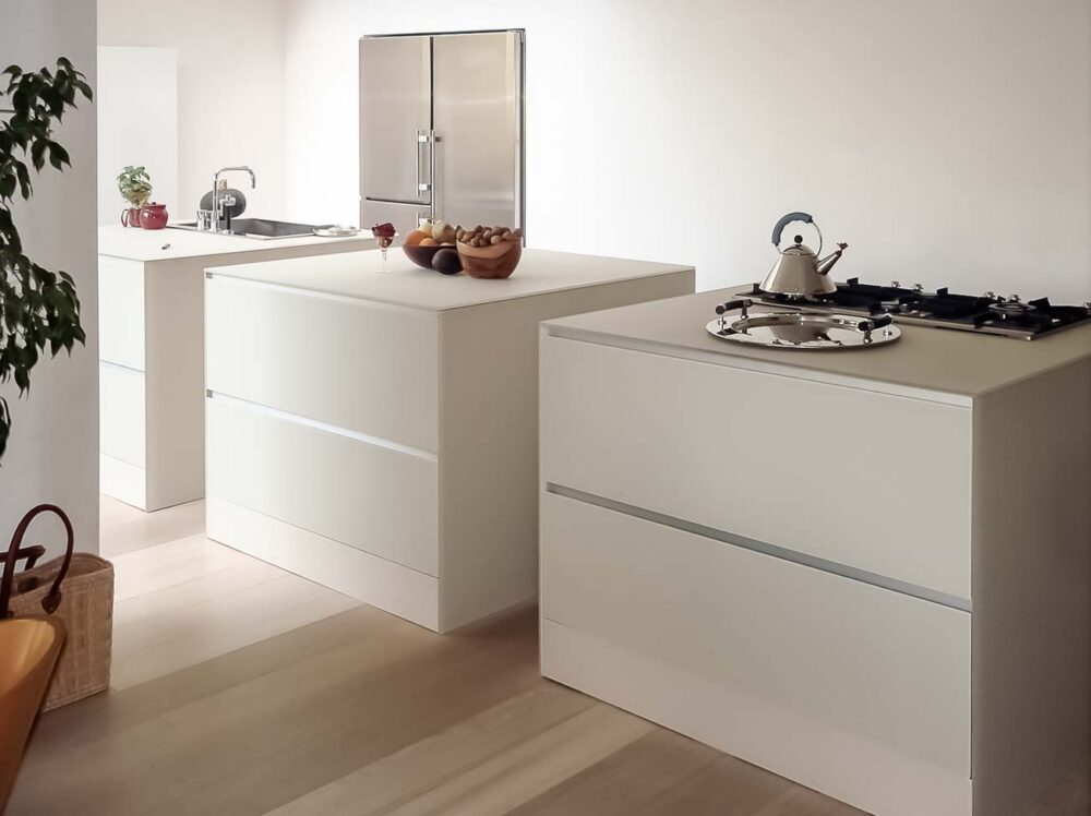 Cuisine avec trois îlots cubiques en verre couleur parchemin, colonnes et frigo américain intégré