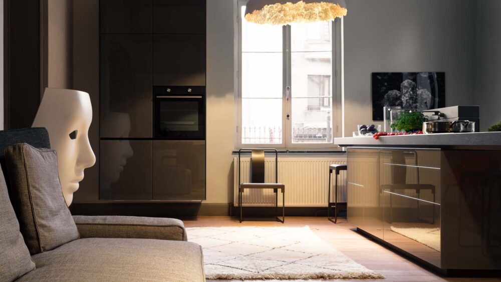 Cuisine avec plan de travail massif en pierre et grandes colonnes en verres gris brillant suspendues à Bruxelles