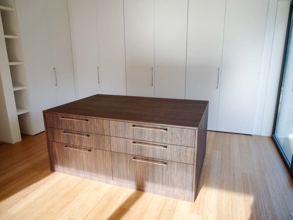 Un dressing minimaliste blanc, avec un meuble central en bois