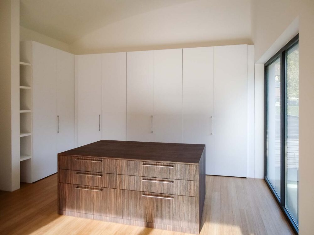 Un dressing minimaliste blanc, avec un meuble central en bois
