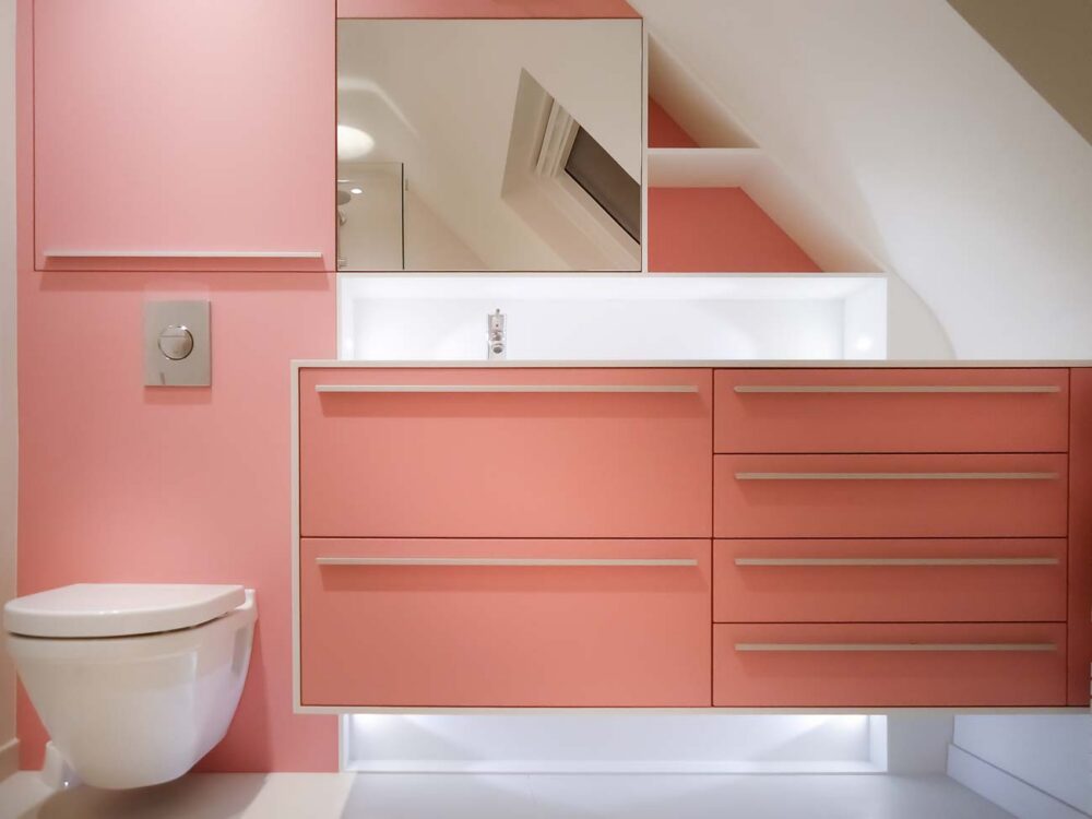 Salle de bain en laqué mat rose et corian blanc sur mesure et WC bâti-support habillé