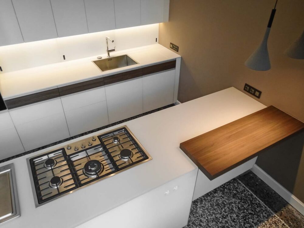 Cuisine avec îlot en verre blanc mat, compositions murales en laqué mat et détails en bois de noyer