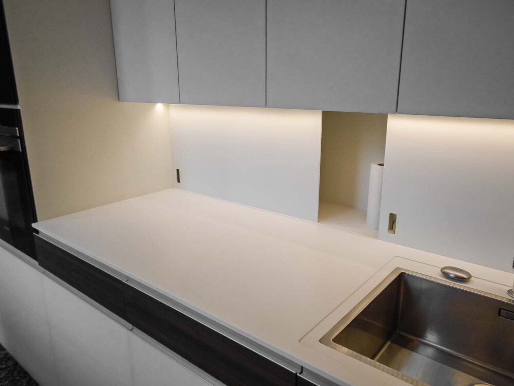 Cuisine avec îlot en verre blanc mat, compositions murales en laqué mat et détails en bois de noyer