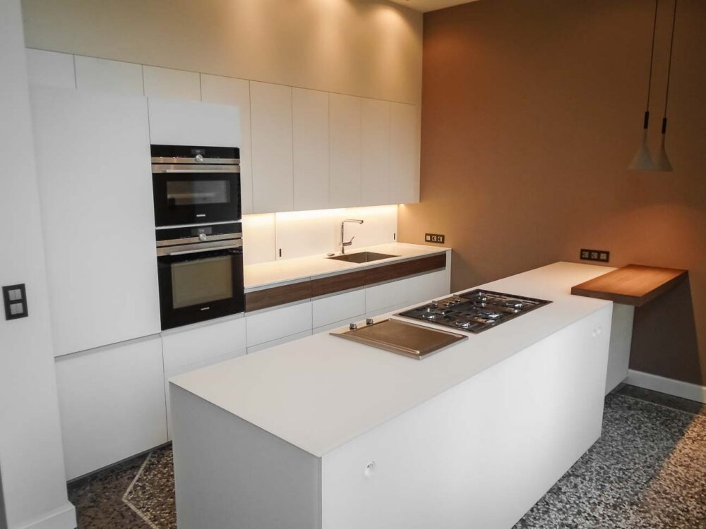 Cuisine avec îlot en verre blanc mat, compositions murales en laqué mat et détails en bois de noyer