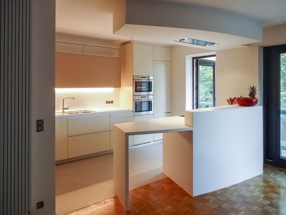 Cuisine en Corian blanc sur mesure, laqué mat crème et verre, aux lignes courbées