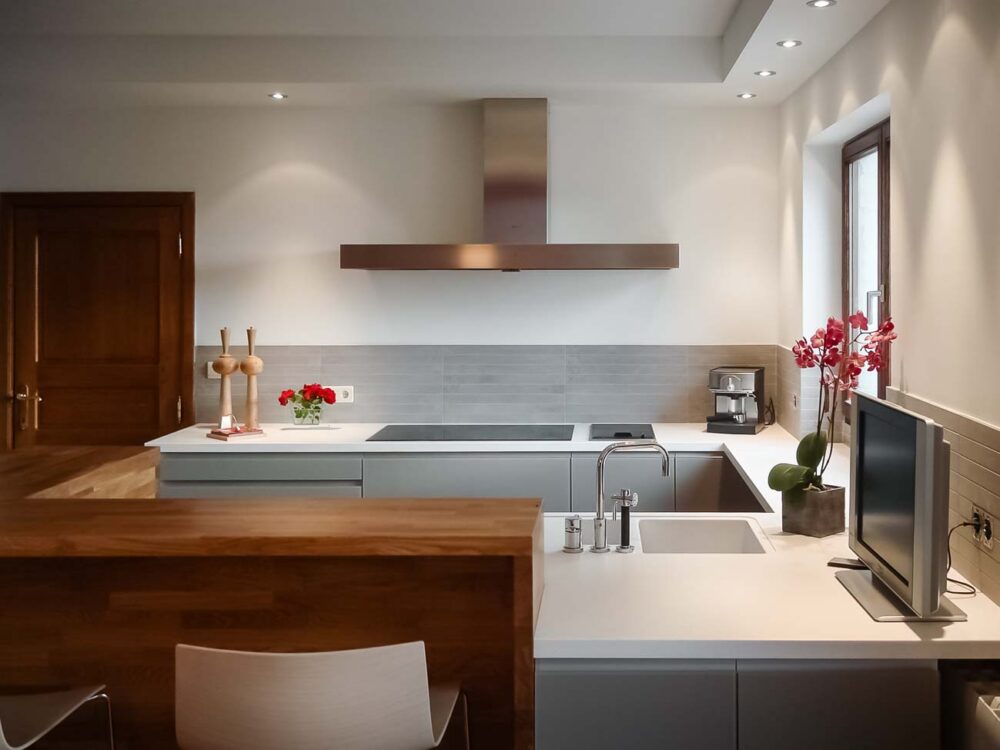 Cuisine en verre gris et plan de travail en Corian blanc avec coin snack en bois massif