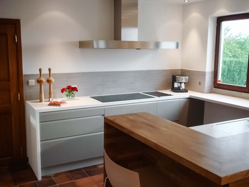 Cuisine en verre gris et plan de travail en Corian blanc avec coin snack en bois massif