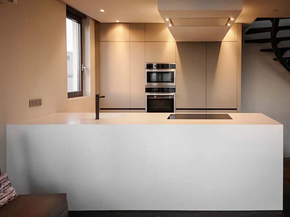 Cuisine design avec îlot en Corian blanc, plaque de cuisson à fleur, colonnes en stratifié gris mat