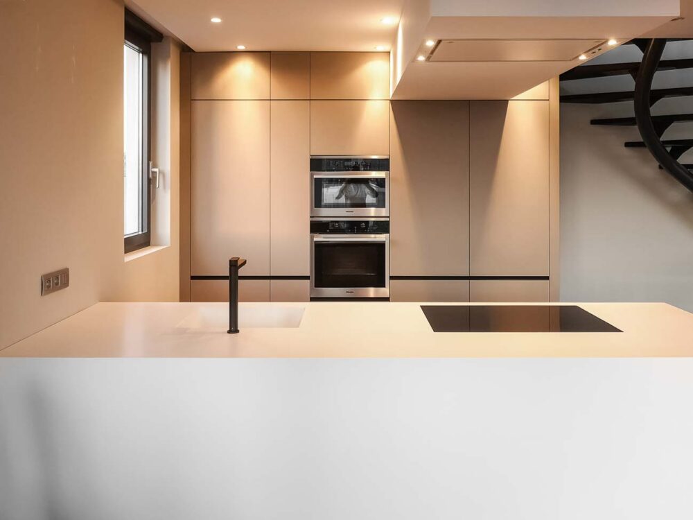 Cuisine design avec îlot en Corian blanc, plaque de cuisson à fleur, colonnes en stratifié gris mat