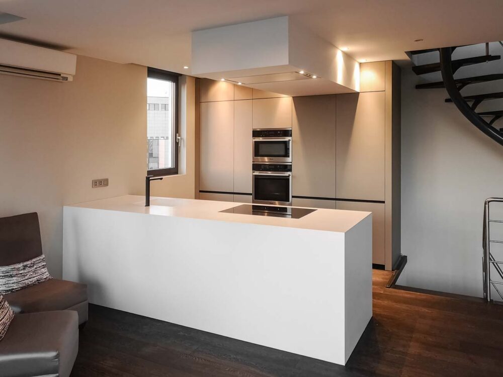 Cuisine design avec îlot en Corian blanc, plaque de cuisson à fleur, colonnes en stratifié gris mat