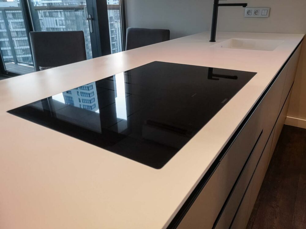 Cuisine design avec îlot en Corian blanc, plaque de cuisson à fleur, colonnes en stratifié gris mat