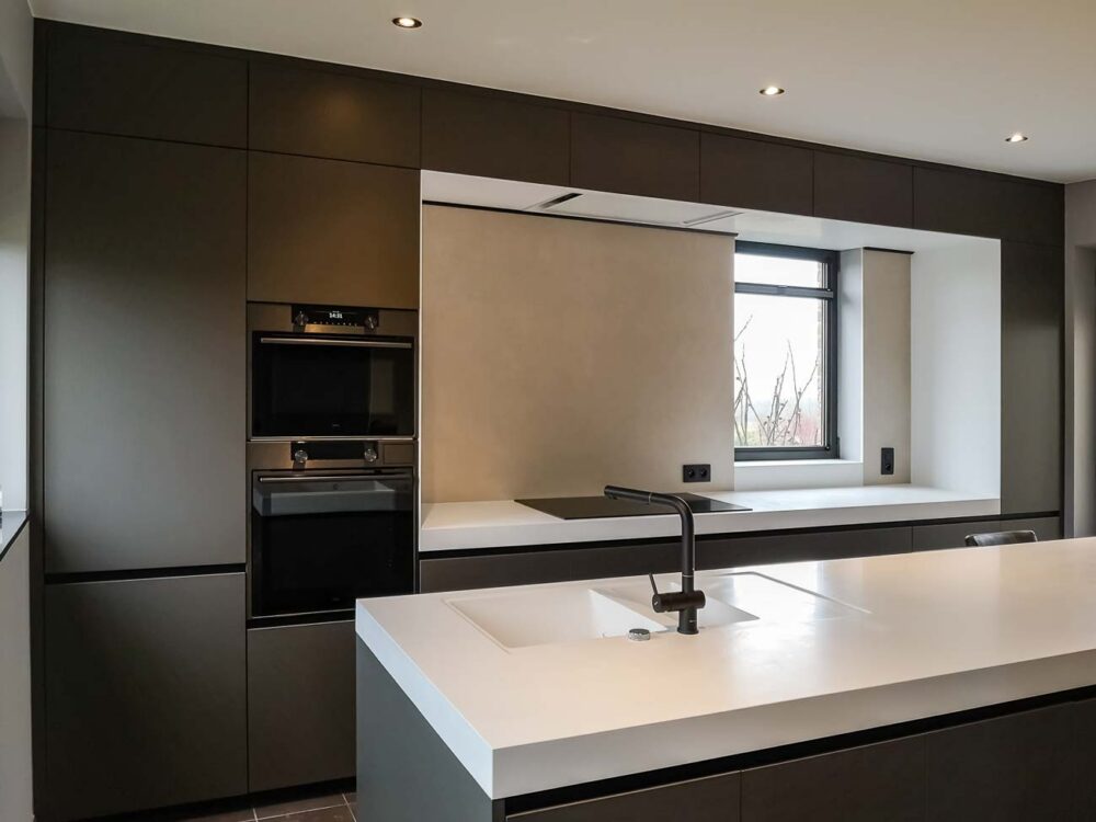 Cuisine laqué mat gris foncé, plan de travail en Corian blanc minimaliste par Christophe Dave en Belgique