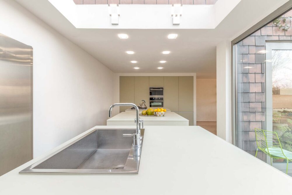 Cuisine avec trois îlots cubiques en verre couleur parchemin, colonnes et frigo américain intégré