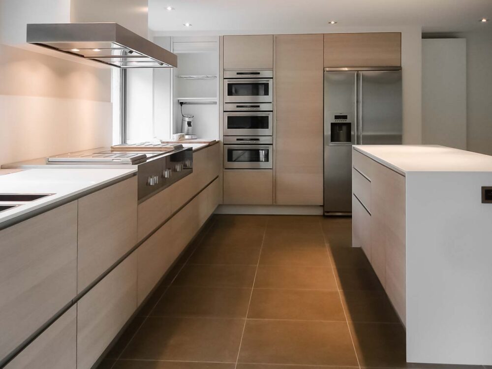 Cuisine entièrement équipée avec îlot monolithe en Corian blanc et portes en plaqué chêne et aluminium