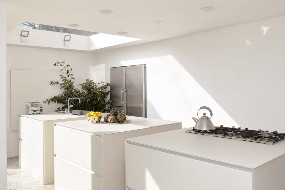 Cuisine avec trois îlots cubiques en verre couleur parchemin, colonnes et frigo américain intégré